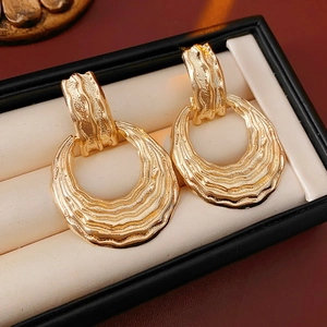 Detail of golden textured crescent earrings displayed in a black jewelry box