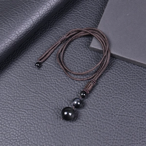 Macro shot of 16mm black obsidian beads on a dark brown braided rope necklace