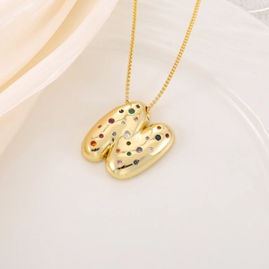 Macro view of gold letter M pendant necklace with colorful cubic zirconia stones