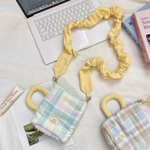 Detail of checkered water bottle bag with ruffled strap and brand logo on bed