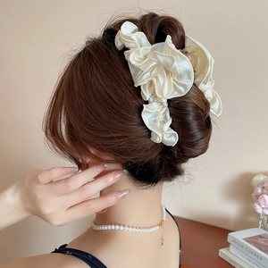 Detail of off-white satin pleated ruffle hair claw clip on model in a french elegant bun
