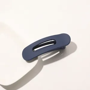 Detail shot of navy blue matte hair clip with hollow design on white ceramic plate