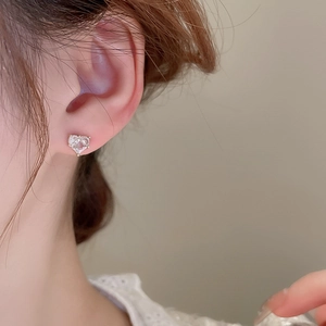Gros plan détaillé d'une boucle d'oreille cœur en zircon portée sur le lobe de l'oreille