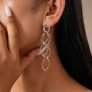 Close-up of layered silver geometric hoop earrings worn by a model in a high-fashion style