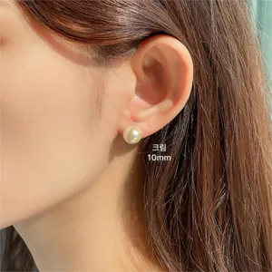 Close-up of 10mm cream pearl stud earrings on model for a minimalist jewelry style