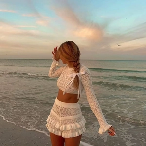 White crochet knit long sleeve crop top and ruffle skirt set on a sunset beach