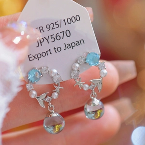 Macro view of 925 silver mermaid tail earrings with blue zircon and pearl charms