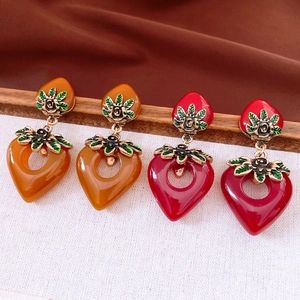 Detail of vintage heart earrings with metallic roses and colorful enamel leaves