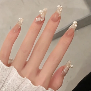 Detail of long ballerina nails with white embossed texture and elegant 3D pearl accents