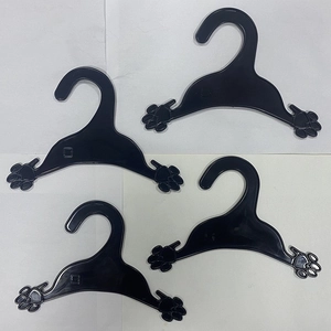 Set of 4 black plastic pet clothing hangers with cute paw print design on a white background
