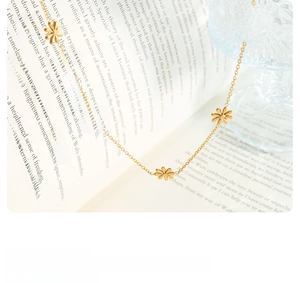 Detail of gold daisy flower necklace with five small floral charms on an open book