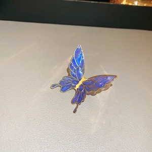 Macro detail of blue gradient enamel butterfly clip earring with gold metal edges