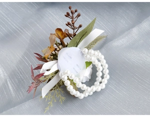 Detail of handmade wrist corsage with white pearls, silk flowers and autumn leaves decor