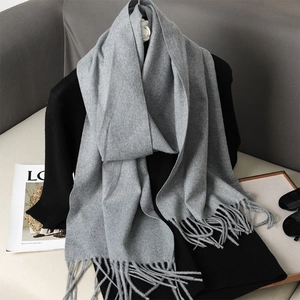 Detailed view of light gray cashmere-feel scarf with long tassels and elegant texture