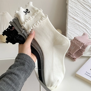 Detail of ruffle trim socks featuring delicate black bow embroidery and ribbed texture