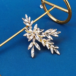 Detail of bridal gold leaf hair clip with marquise rhinestones on a blue background