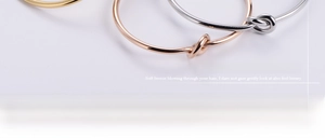 Close-up of minimalist knot bangles in gold, silver, and rose gold stainless steel