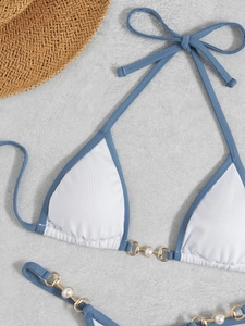 Detail of white ribbed bikini top with blue trim and elegant pearl gold chain straps
