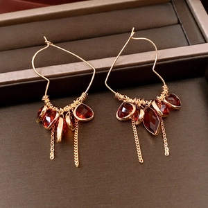 Detailed close-up of 18K gold-plated heart earrings with red glass tassels and vintage finish