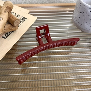 Close-up of deep red square hair claw clip on glass surface with festive setting