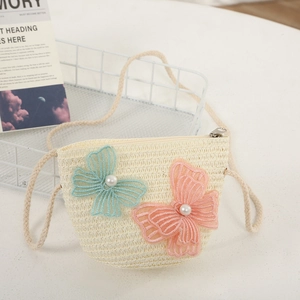 Detailed view of a beige woven crossbody bag with butterfly embroidery and pearl accents