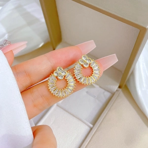 Close-up of gold geometric tassel earrings with zircon inlay on a finger for size guide
