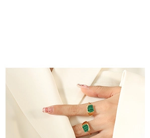 Detail of gold-plated rings featuring green malachite stone worn on model hand