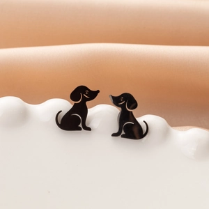 Close-up of black dog silhouette stud earrings on a white tray with silk background