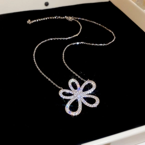Detailed top view of sparkling silver hollow flower pendant necklace on black velvet