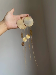 Detailed macro shot of golden textured round plate earrings with long tassel chain fringe