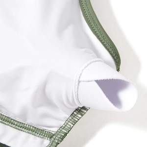Detail of high-stretch white swimsuit with olive green piping and internal pad pockets