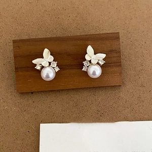 Detailed close-up of golden butterfly pearl earrings with sparkling zircon accents