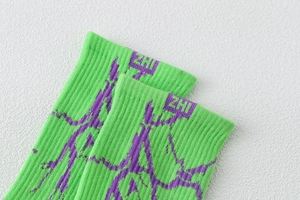 Détail de chaussettes en coton vert néon avec motifs éclairs violets et bords côtes