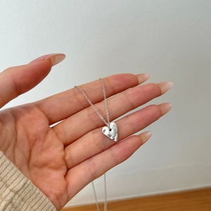 Detail of the irregular heart pendant in brushed silver with sparkling zircon accents