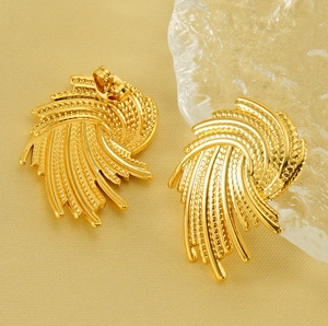 Macro detail of gold-plated vortex earrings showing fine grain texture and back clasp