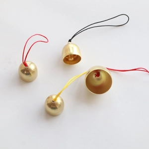 Detail of 2cm mini metal bells with colorful hanging cords on a clean white background