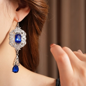 Detail of vintage teardrop earrings featuring deep blue crystals and silver filigree design