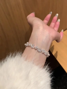 Detail of elegant pearl and zircon bracelet on wrist with white plush cuff