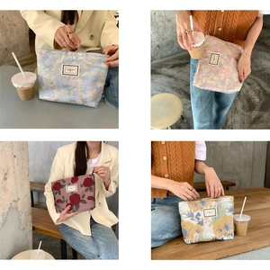 Close-up of four floral jacquard makeup bags with zippers on a rustic wooden table