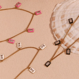 Detailed view of rectangular gold pendants with pink white and black enamel and zircons