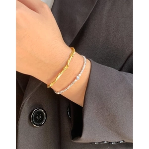 Elegant gold woven bangle and silver irregular bead bracelet stack on a wrist