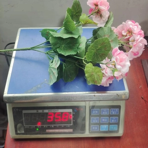 Pink artificial geranium bouquet on a digital scale showing a weight of 358g