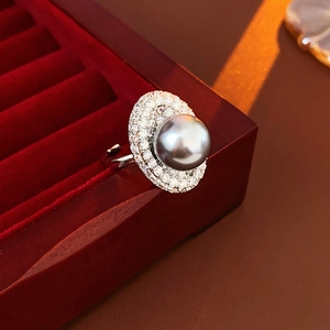 Macro detail of a silver ring with a grey pearl and diamonds in a red velvet box