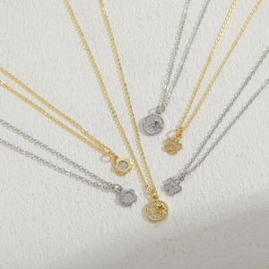 Minimalist gold and silver necklaces with clover and star pendants set on a soft fabric