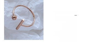 Detail of rose gold open ring featuring a minimalist sphere and cylindrical geometric design