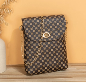 Dettaglio borsa a tracolla vintage con stampa trifoglio oro, chiusura girevole e catena