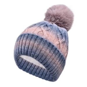 Detailed cable knit texture on pink and blue gradient winter hat with fluffy faux fur pompom