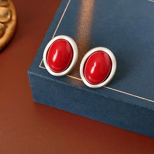 Close-up of vintage oval red gemstone earrings set in a matte silver metal frame