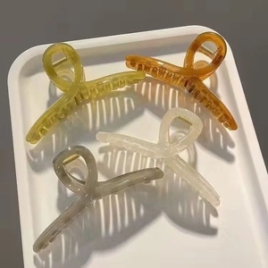 Detailed close-up of large criss-cross hair claws in amber, olive green and cream resin