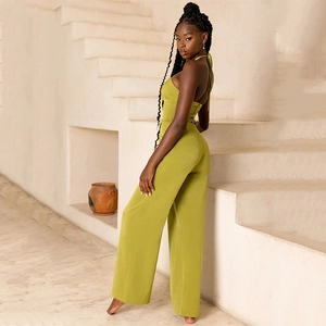 Olive green halter neck wide leg jumpsuit for women in a minimalist architectural setting